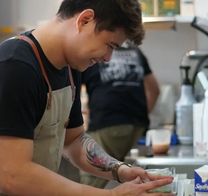 Daily Grind barista smiling while making a matcha drink
