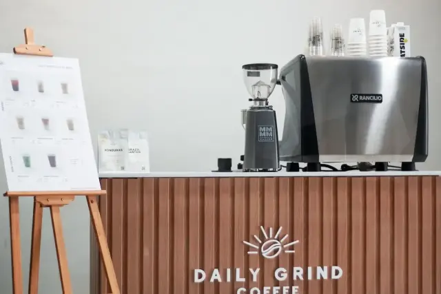 Daily Grind mobile coffee bar with an espresso machine, grinder and a drinks menu on an easel