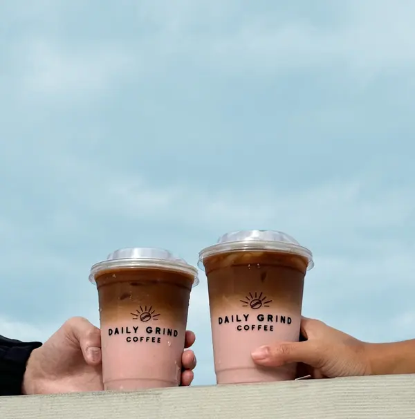 Two strawberry lattes held up against the sky