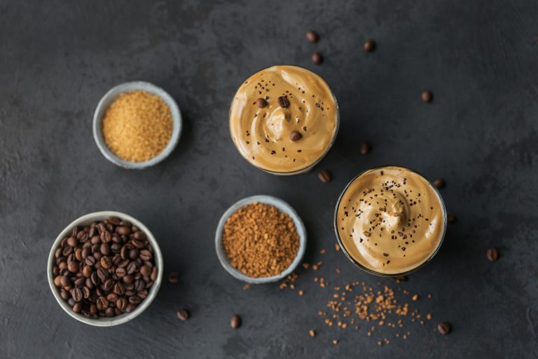 Glass of Iced Dalgona Coffee, trendy fluffy creamy whipped coffee and milk on black background.